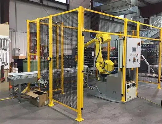 A robotic cell partially surrounded by safety fencing